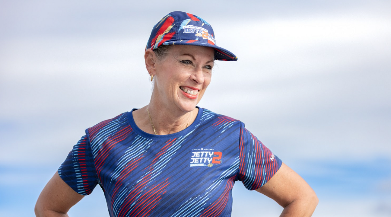 A runner smiling in the United Airlines Jetty 2 Jetty running cap and jersey by Yeah Buddy