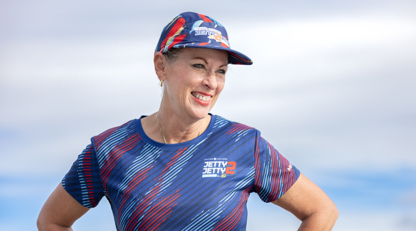 A runner smiling in the United Airlines Jetty 2 Jetty running cap and jersey by Yeah Buddy